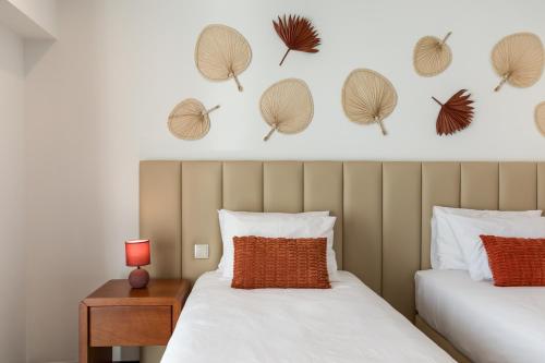een slaapkamer met 2 bedden en een muur met bladeren erop bij Viravento - Guesthouse & Creative Space in Espinho