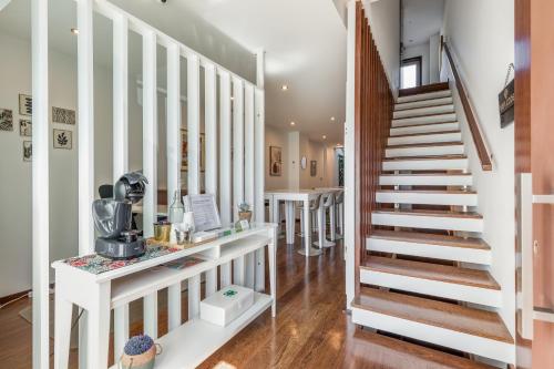 una escalera en una casa con paredes blancas y suelo de madera en Viravento - Guesthouse & Creative Space en Espinho