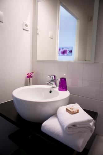 une salle de bain avec un lavabo, un miroir et des serviettes dans l'établissement Hôtel Anaïade, The Originals City, Saint-Nazaire Pornichet, à Saint-Nazaire