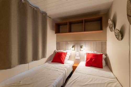 two beds in a room with red pillows at Maïana Resort in La Grande-Motte