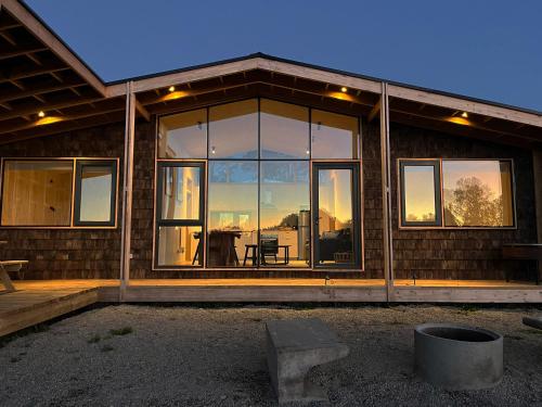 a house with glass windows and a table in it at Cabaña en Rio Maullin Nek #1 in Las Quemas del Salto