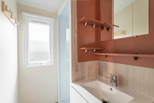 a bathroom with a tub and a sink and a window at Maïana Resort in La Grande Motte