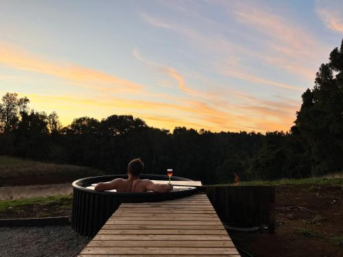 a man in a bath tub with a glass of wine at Cabaña en Rio Maullin Nek #1 in Las Quemas del Salto