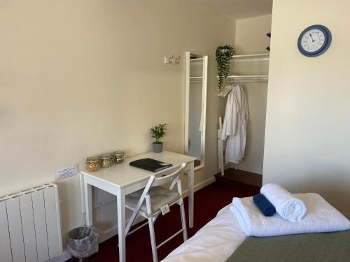een kamer met een bureau, een bed en een klok bij The Ivy Barn Holbeton in Plymouth