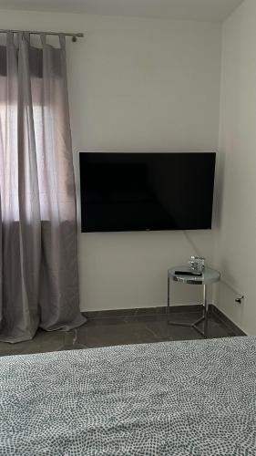 a flat screen tv on a white wall with a table at Luxus-Flat Wohnung-Hanau/Frankfurt in Hanau am Main
