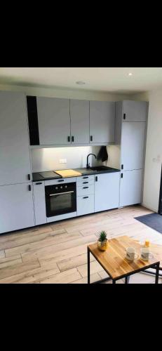 une cuisine avec des armoires blanches et une table en bois dans l'établissement Studio cosy dans l’Esterel proche Mer, à St Jean de l’Esterel