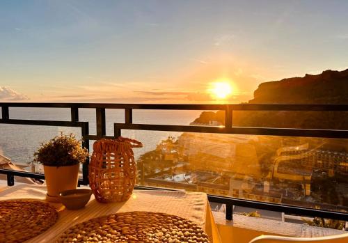 a table with food on top of a balcony with the sunset at Sea view - Big Terrace - Sunset in Taurito