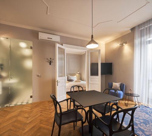 uma sala de estar com uma mesa e cadeiras e uma cama em URBANAUTS BELETAGES Sonata em Trieste