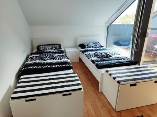 two beds in a room with a window at Ferienwohnung "Zur alten Schreinerei" Gundelfingen - Donau in Gundelfingen