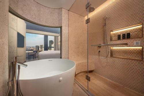 a bathroom with a white tub and a glass window at Hotel Indigo Wuxi Taihu New City in Wuxi