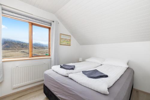 a white bedroom with a bed with towels on it at Guesthouse Rauðafell in Holt