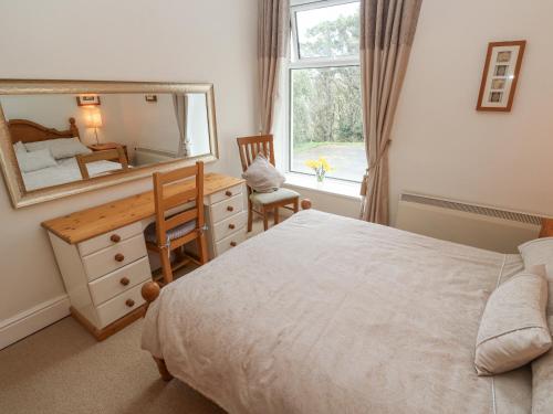 a bedroom with a bed and a desk and a mirror at Seaview in Coverack