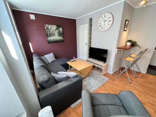 a living room with a couch and a clock on the wall at Central 1BR Apartment in Narvik