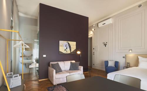 um quarto de hotel com uma cama, um sofá e uma cadeira em URBANAUTS BELETAGES Sonata em Trieste