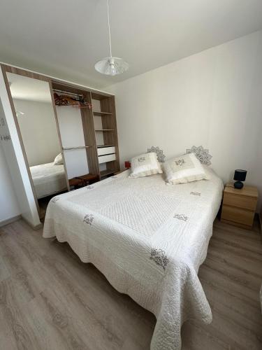 une chambre avec un lit avec des draps blancs et un miroir dans l'établissement Chez Tina jolie maison à 12 min du Puy du Fou, aux Herbiers