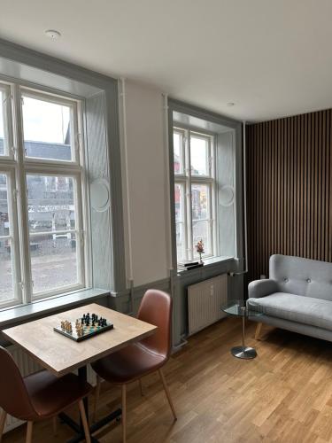 a living room with a table and a couch and windows at VISIONHOUSE Hotel in Frederikssund