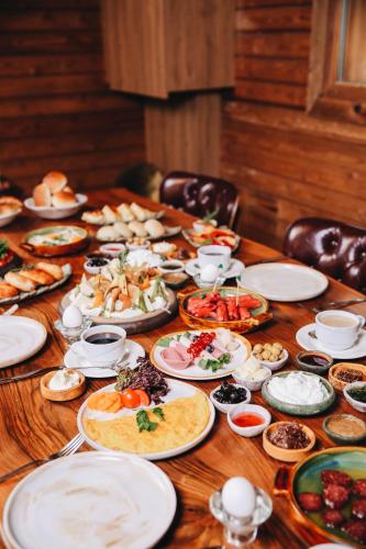 a wooden table with plates of food on it at Karinna Orman Evleri & Non Alcohol in Uludag