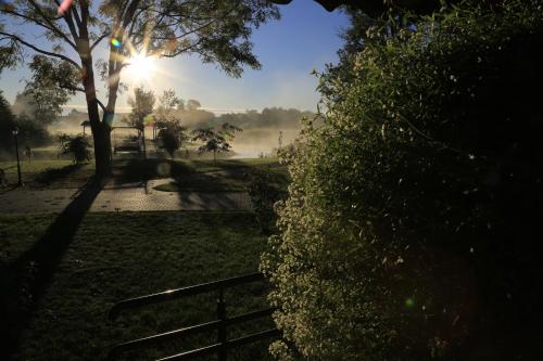 a park with a fence and the sun in the background at Pensjonat Bajdarka in Suraż
