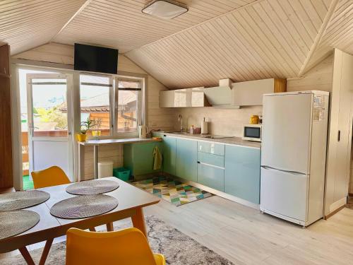 a kitchen with a table and a white refrigerator at Три-О Апартаменти з балконом, без сусідів за стінкою, для 2-4 осіб in Slavske