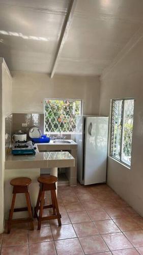 een keuken met een witte koelkast en 2 krukken bij Villa 8 personas in Puntarenas