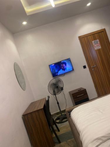 1 dormitorio con 1 cama, ventilador y TV en BLUE AO HOTEL AND SUITES, en Lagos
