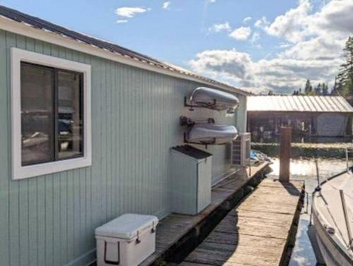 a house with a deck with a grill on it at Boats N Rows Float Home in Athol