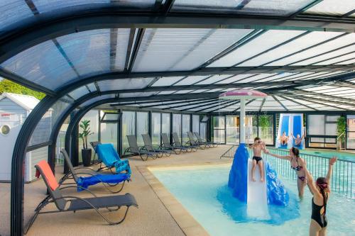 une piscine avec deux filles jouant dans l'eau dans l'établissement Camping Les Pommiers du Mont Saint Michel, à Beauvoir