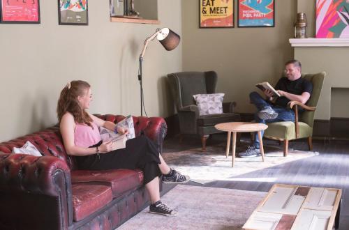 two people sitting on a couch in a living room at Malacuna Liverpool in Liverpool