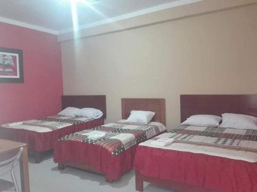 duas camas num quarto com paredes vermelhas em Hostal Los Angeles em Tarapoto
