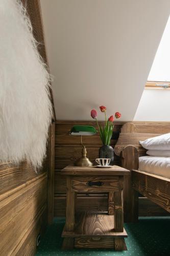 a room with a bed and a table with flowers on it at Pokoje Gościnne Biały Bizon in Rabka