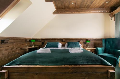 1 dormitorio con 1 cama verde y 2 sillas azules en Pokoje Gościnne Biały Bizon, en Rabka