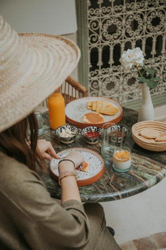 een vrouw die aan een tafel zit met een bord eten bij Riad Dar M in Marrakesh