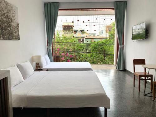 two beds in a room with a large window at LaRose Cafe I Bed & Breakfast in Quy Nhon