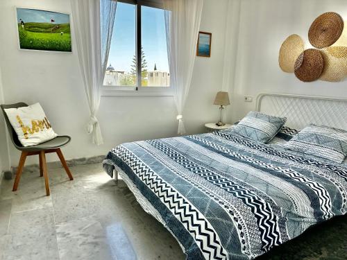 sypialnia z łóżkiem, krzesłem i oknem w obiekcie Bright apartment 300m from the beach w mieście Sitio de Calahonda