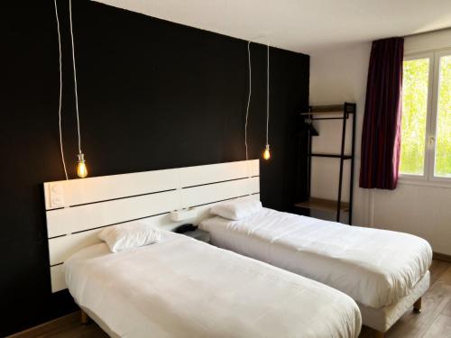 two beds in a room with a black wall at Brit Hotel Confort Gien in Gien