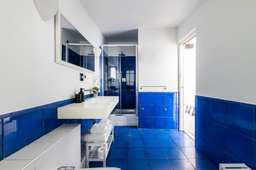 La salle de bains bleue est pourvue d'un lavabo blanc et de carrelage bleu. dans l'établissement Easylife - Suite in Colonne San Lorenzo Milano, à Milan
