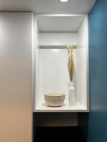 a shelf with a bowl and a vase with flowers in it at Homevision - Galerius Arch Condo - City Center in Thessaloniki