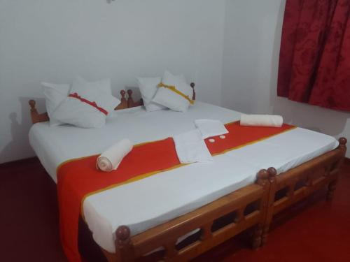 a bedroom with two beds with white and red sheets at Beach Walk Villa in Trincomalee