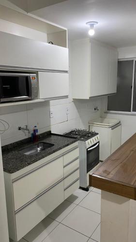 eine Küche mit weißen Schränken und einem Herd mit Backofen in der Unterkunft Park marilandia 507 in Juiz de Fora