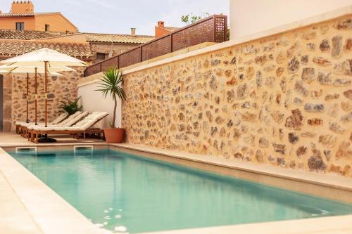 a swimming pool in front of a stone wall at Ōrigins Hotel Boutique - Adults Only in Artá