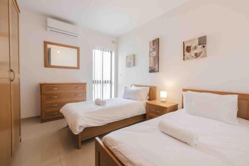 a bedroom with two beds and a window at Blossom Bliss apartment in Msida