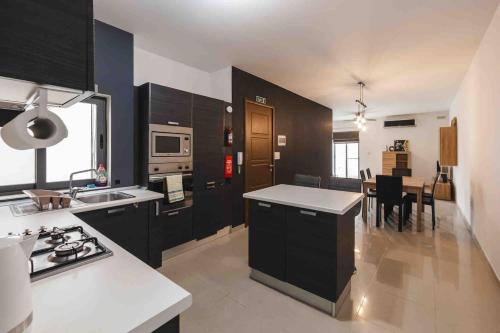 una cucina con armadi neri e piano di lavoro bianco di Blossom Bliss apartment a Msida