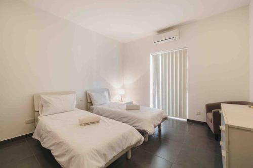 two beds in a room with a window at Hidden Gem in Sliema