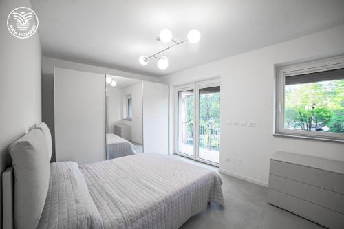 a white bedroom with a bed and a window at RESIDENCE BAIA RILKE in Sistiana