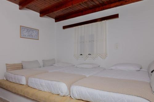 two beds in a room with white walls at Spot on the sea in Archangelos