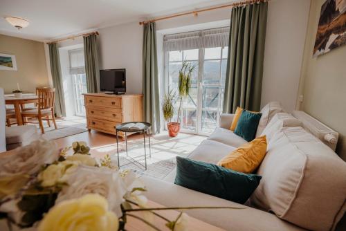 ein Wohnzimmer mit einem weißen Sofa und einem TV in der Unterkunft Ferienwohnungen Hotel Garni Dörflerwirt in Aflenz Kurort