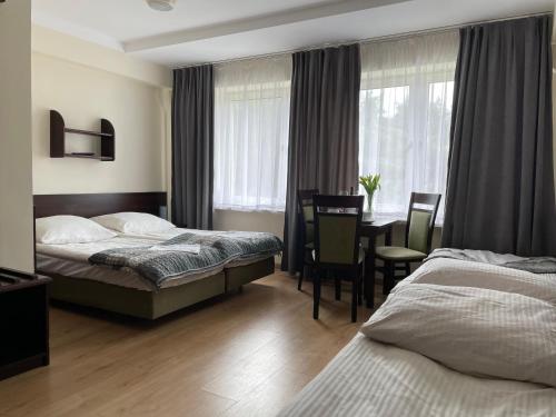 pokój hotelowy z 2 łóżkami, stołem i krzesłami w obiekcie Słowińska Perła w Rowach