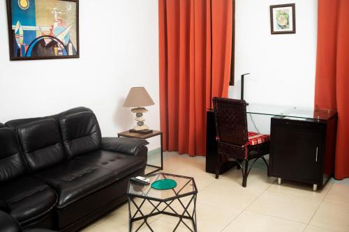 a living room with a black leather couch and a glass table at Hotel le Pelican in Lomé