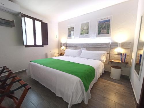 a bedroom with a large bed with a green blanket at LA JARANA Casa Hotel in Zahara de la Sierra