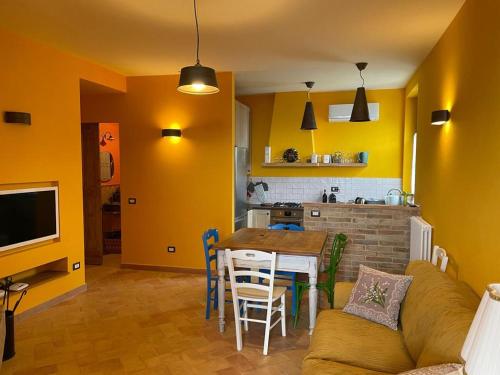 sala de estar con mesa y cocina con paredes amarillas. en Antico Casale San Lorenzo en Colle San Lorenzo